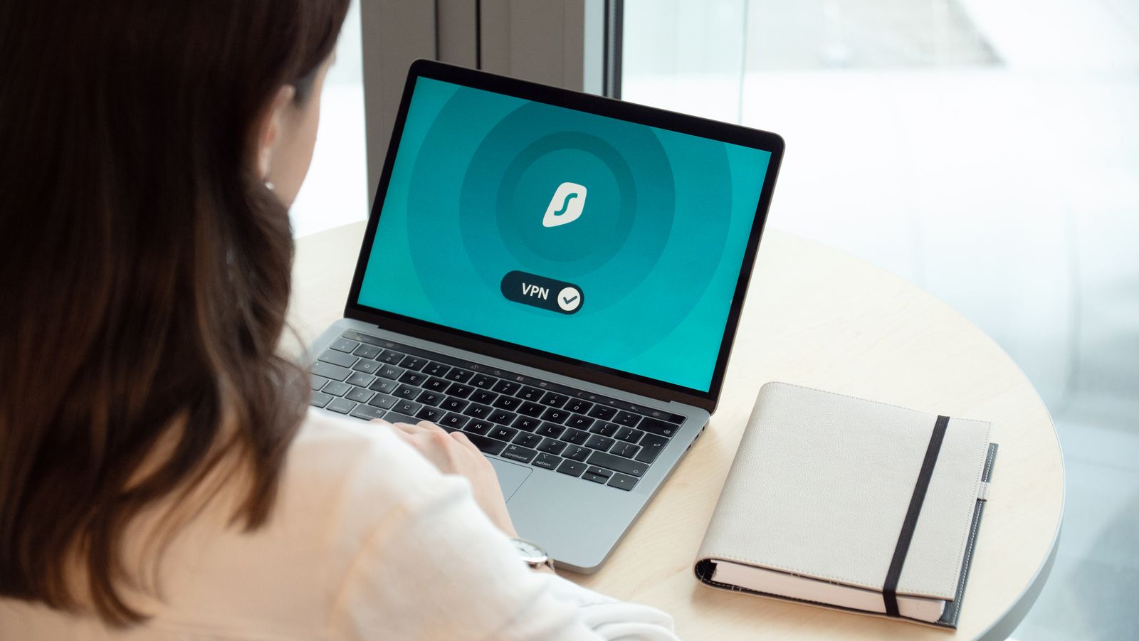 Woman working on a laptop with a VPN icon on screen, representing secure online browsing and data protection for UK ecommerce